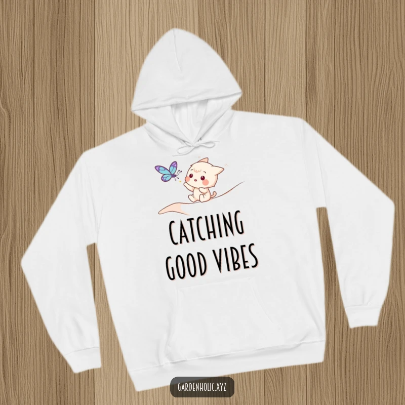 Funny hoodie with a playful character trying to gently catch a fluttering butterfly in a serene outdoor setting.