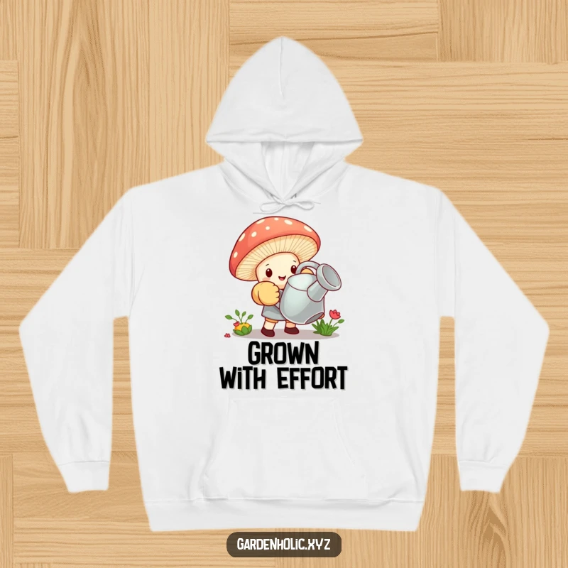 Funny hoodie with a tiny mushroom wearing huge gardening gloves, struggling to lift a giant watering can, symbolizing dedication.